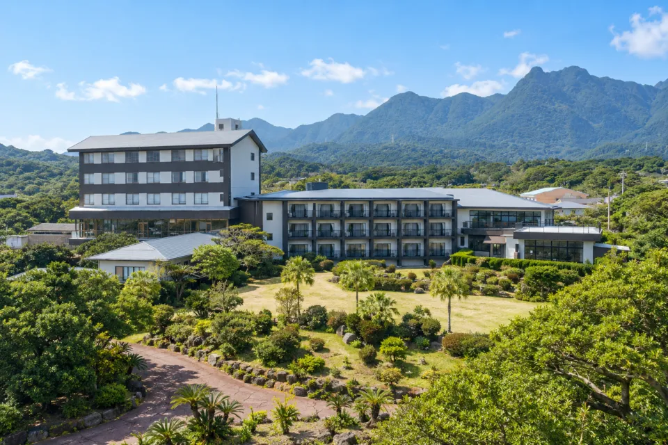 屋久島グリーンホテルの山並みと庭園に囲まれたホテルの外観