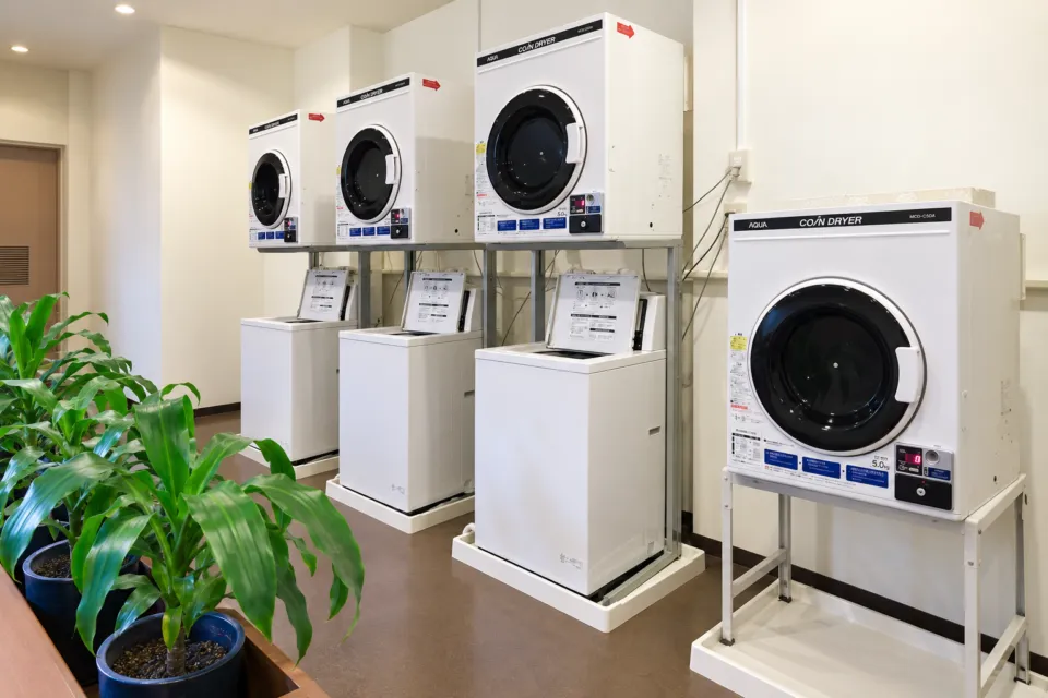 屋久島いわさきホテルの白い洗濯機と乾燥機を備えたコインランドリー